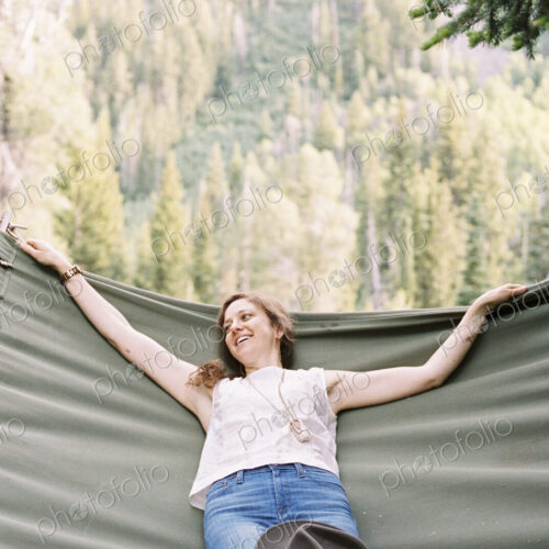 Woman relaxing in a large hammock in a forest.