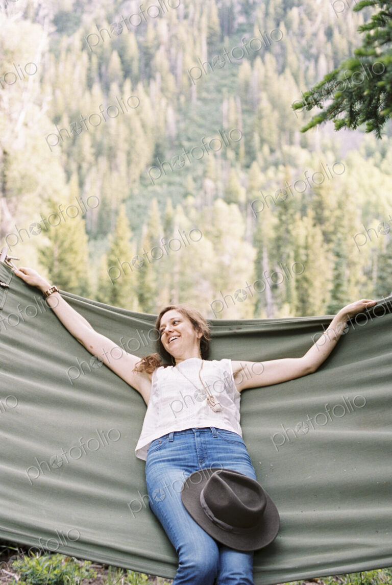 Woman relaxing in a large hammock in a forest.