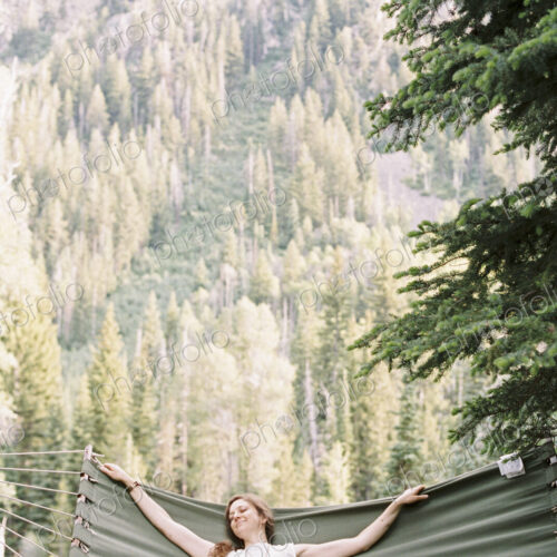 Woman relaxing in a large hammock in a forest.