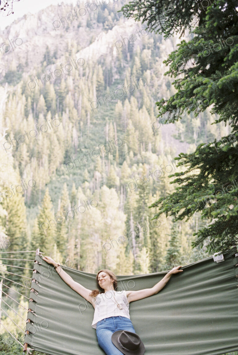 Woman relaxing in a large hammock in a forest.