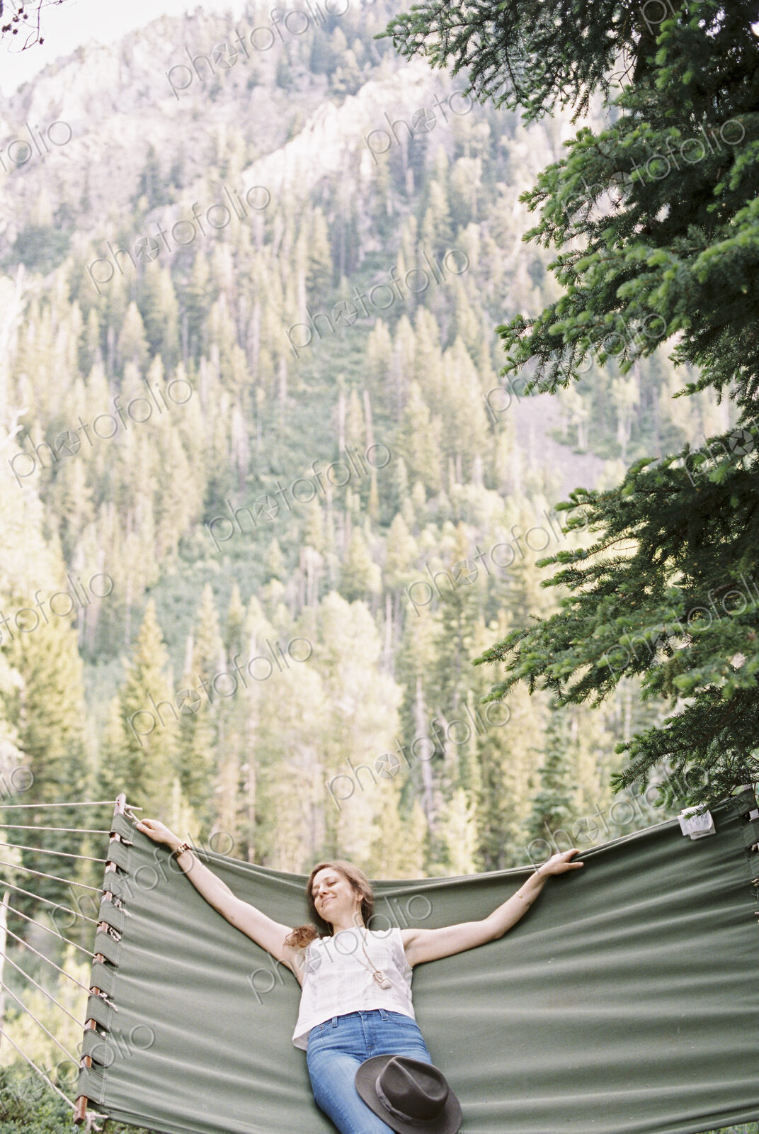 Woman relaxing in a large hammock in a forest.