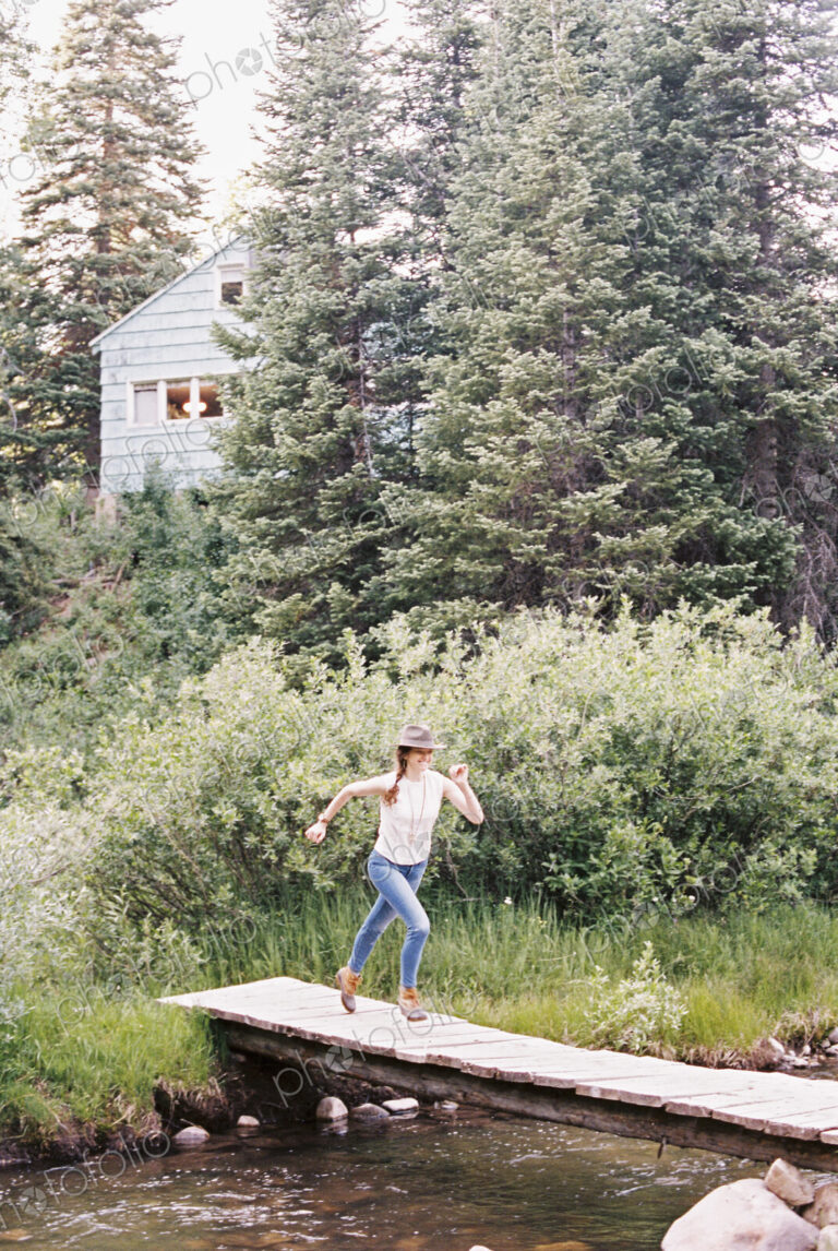 Woman running across a wooden bridge over a stream.