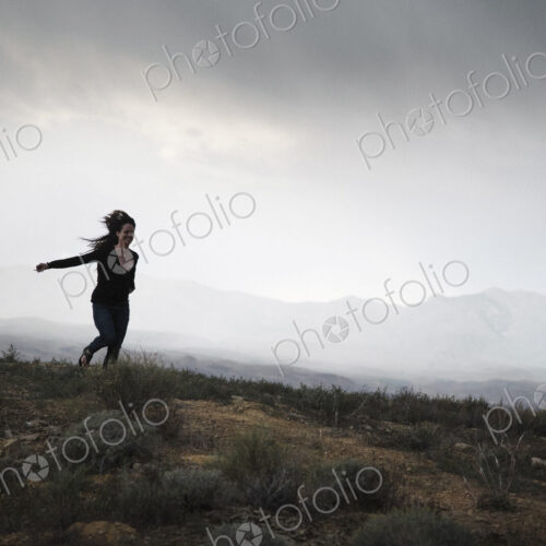 Woman running in a prairie under a cloudy sky. Woman running in a prairie under a cloudy sky.
