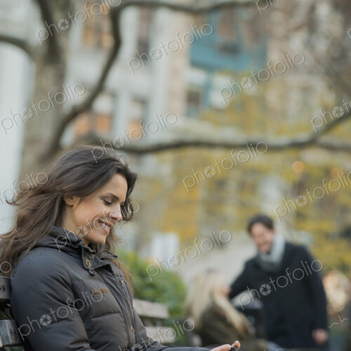 Woman seated in urban park with smartphone Woman seated in urban park with smartphone