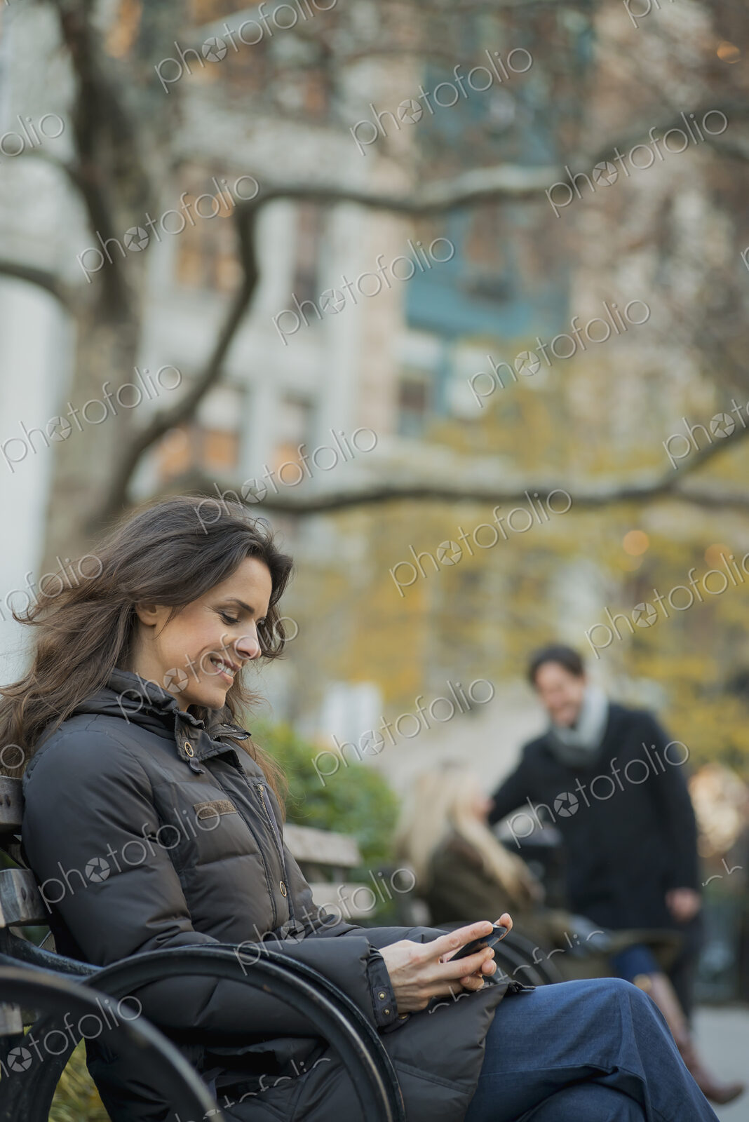 Woman seated in urban park with smartphone