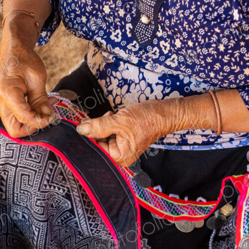 Woman seated stitching, making tradtional garments, Vang Vieng, Laos Woman seated stitching, making tradtional garments, Vang Vieng, Laos