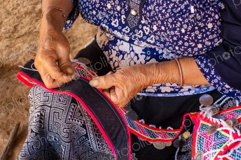 Woman seated stitching, making tradtional garments, Vang Vieng, Laos