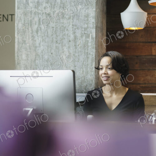 Woman sitting at reception desk in front of a computer.