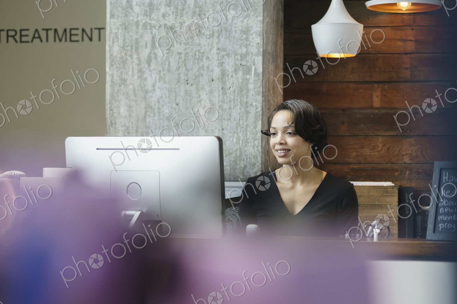 Woman sitting at reception desk in front of a computer.