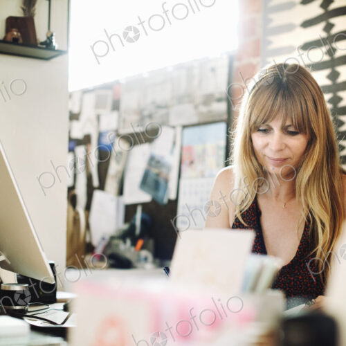 Woman sitting in an office at a desk with a computer, working.