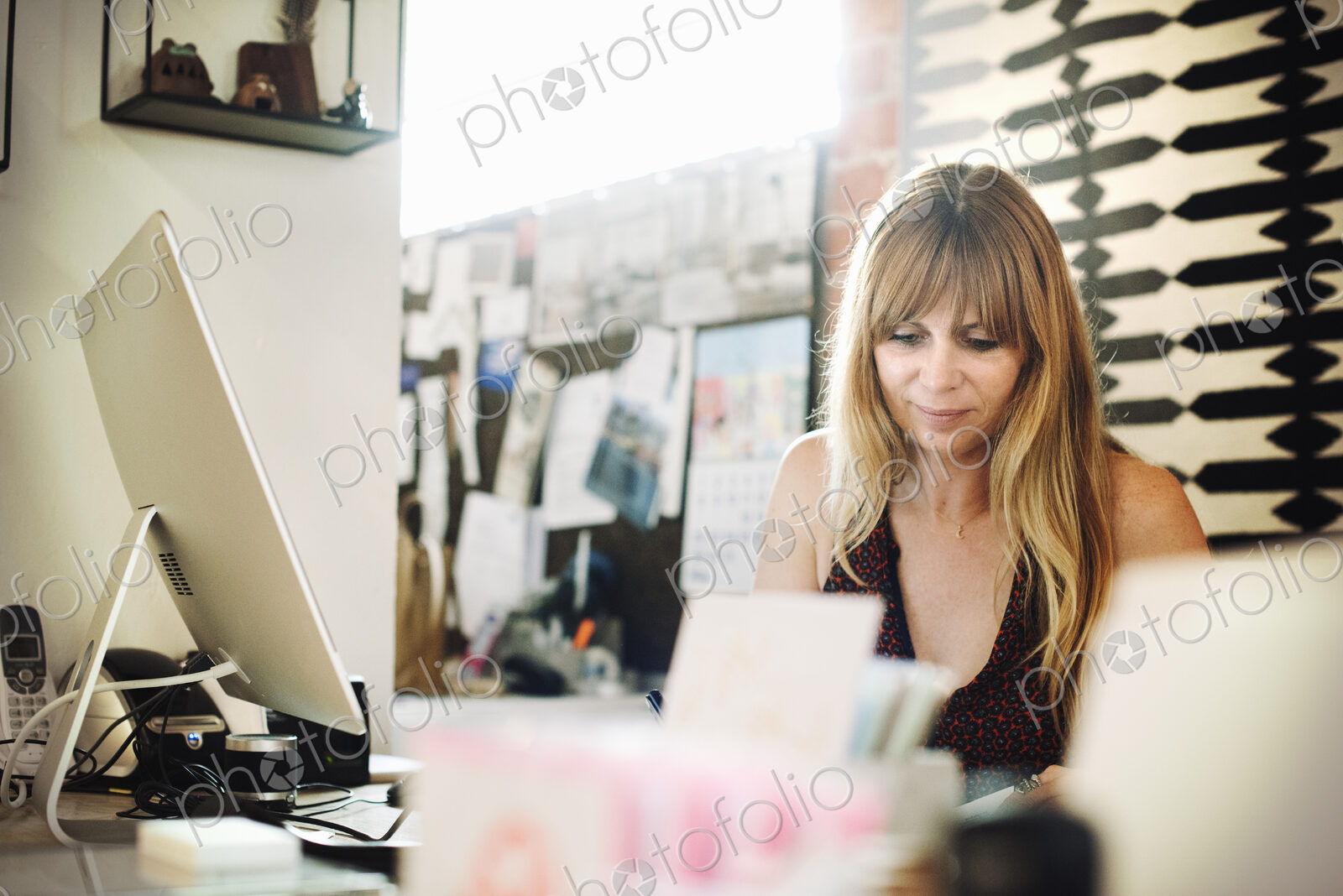 Woman sitting in an office at a desk with a computer, working.
