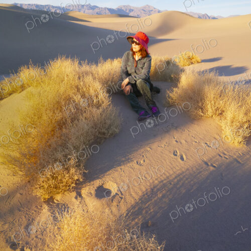 Woman sitting in the sand in Death Valley at sunrise.