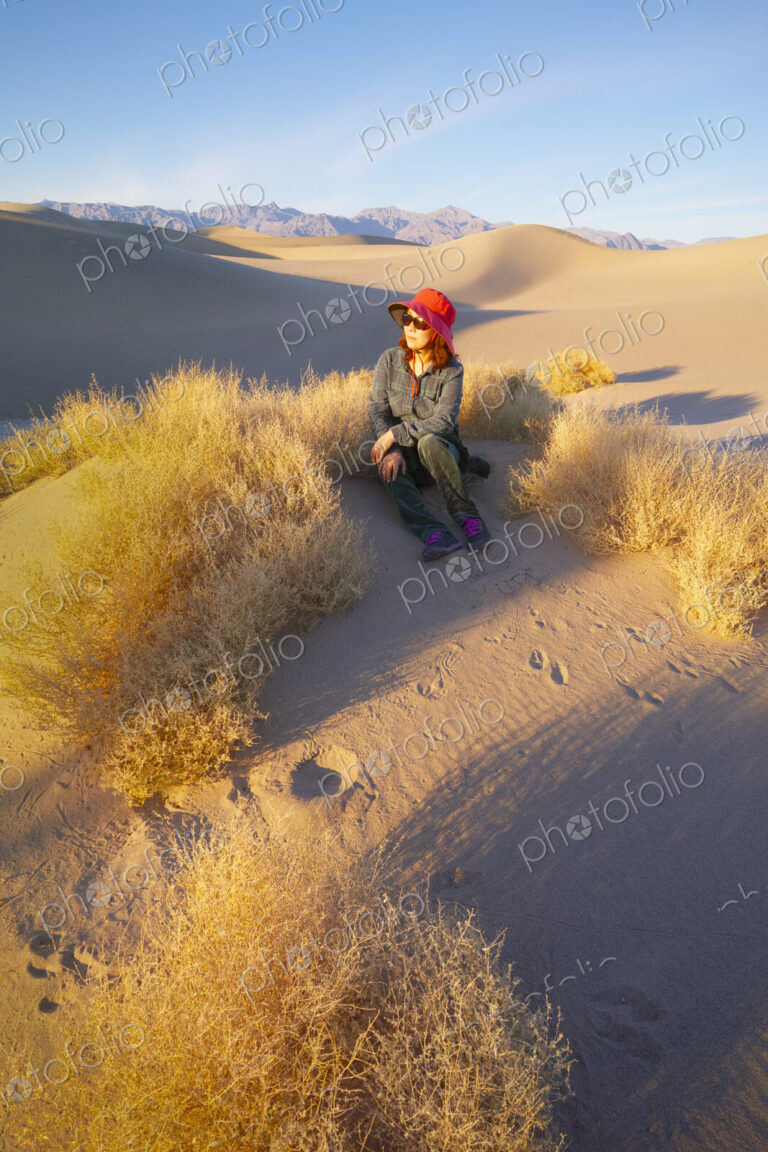 Woman sitting in the sand in Death Valley at sunrise.