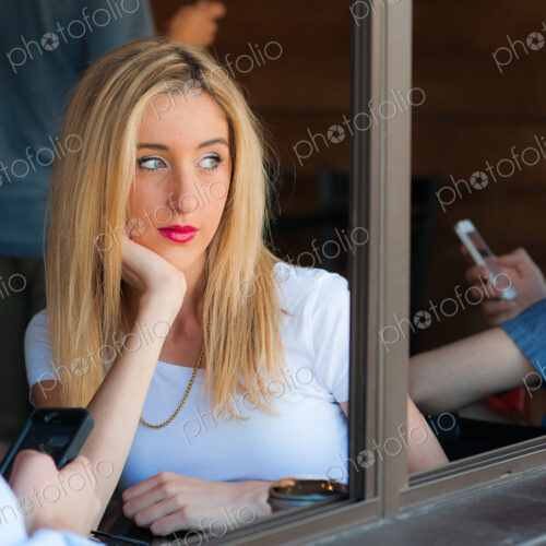 Woman sitting looking out of cafe window while other people use smartphones. Woman sitting looking out of cafe window while other people use smartphones.