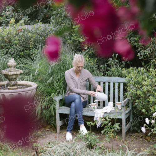 Woman sitting on a wooden bench in a garden, taking a break. Woman sitting on a wooden bench in a garden, taking a break.