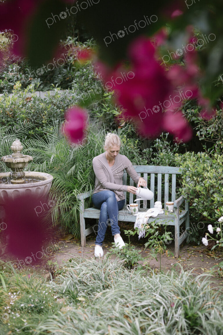 Woman sitting on a wooden bench in a garden, taking a break.