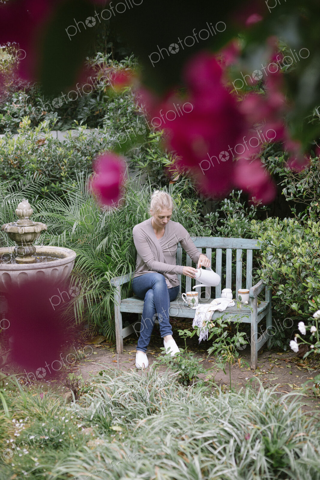 Woman sitting on a wooden bench in a garden, taking a break.