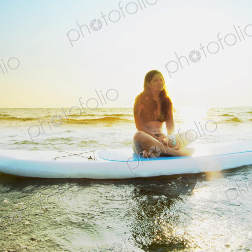 Woman sitting on paddleboard in lake Woman sitting on paddleboard in lake