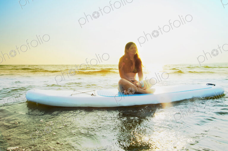 Woman sitting on paddleboard in lake