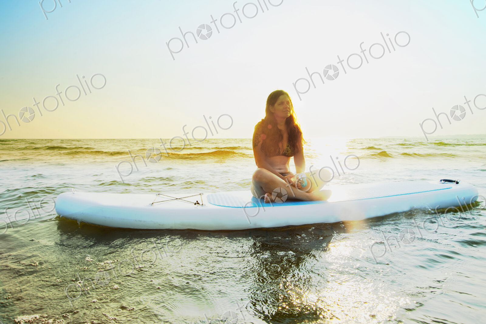 Woman sitting on paddleboard in lake