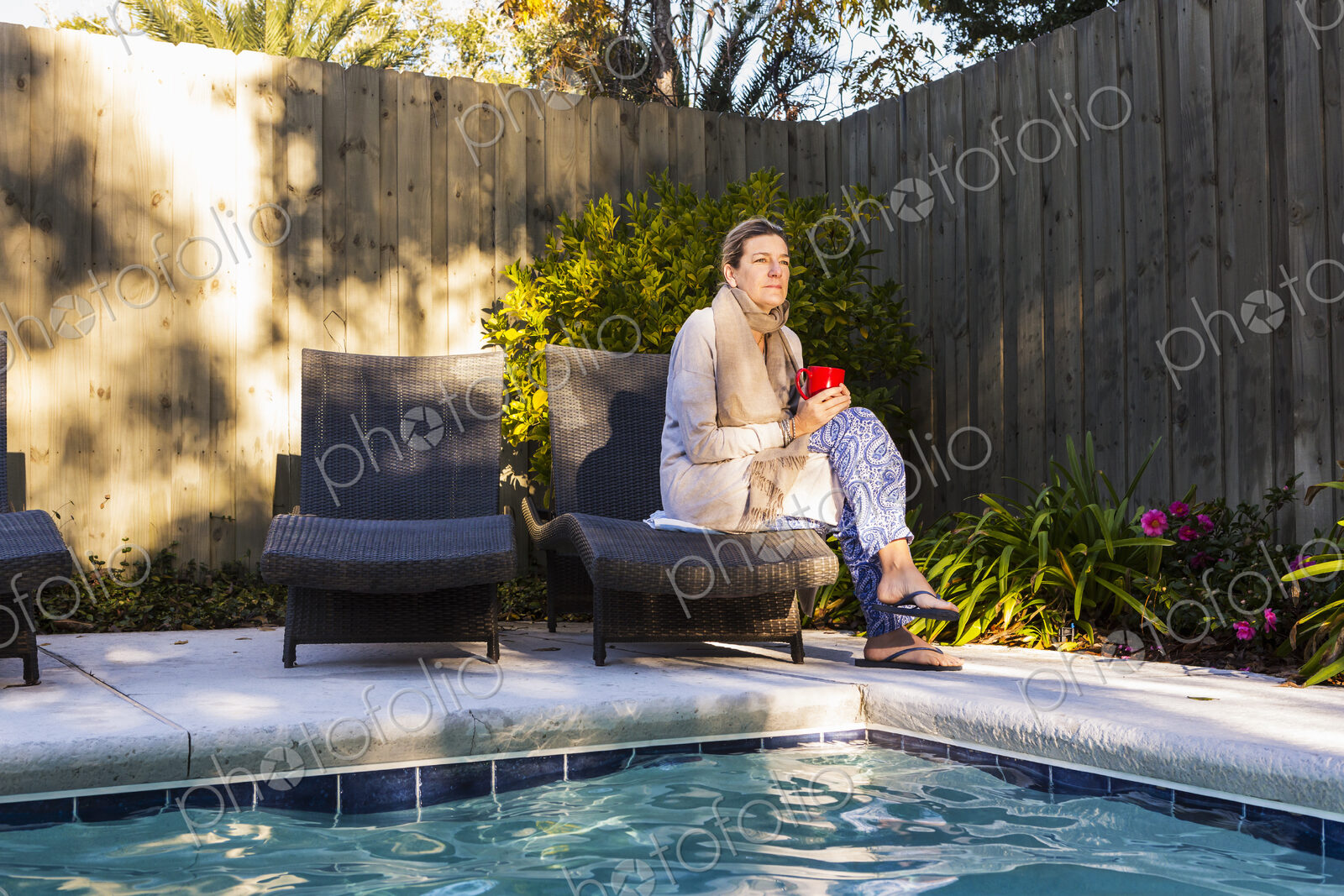 Woman sitting on sun lounger by a swimming pool