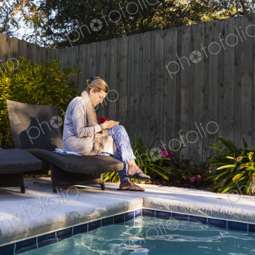 Woman sitting on sun lounger by a swimming pool