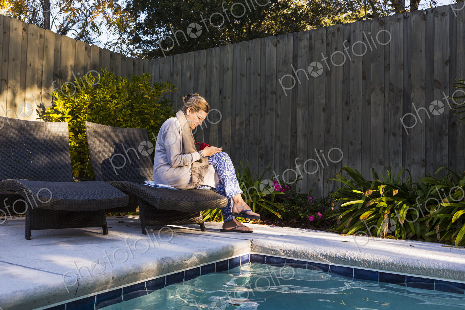 Woman sitting on sun lounger by a swimming pool