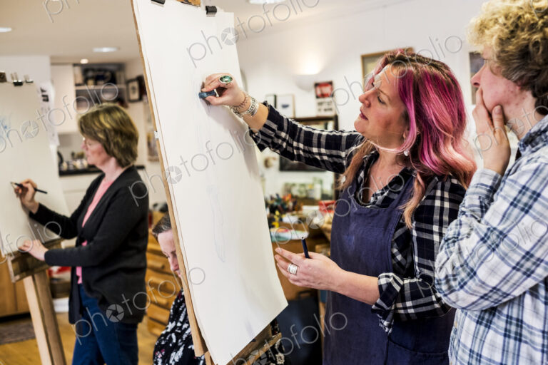Woman standing at an easel, drawing a human leg at a life drawing glass.