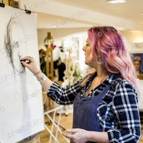 Woman standing at an easel drawing a portrait.