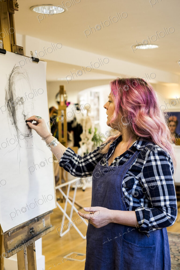 Woman standing at an easel drawing a portrait.