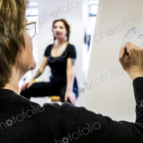 Woman standing at easel, drawing human hand at life drawing class