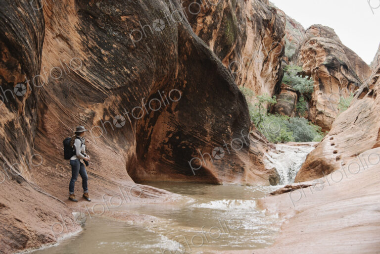 Woman standing by river in a canyon.
