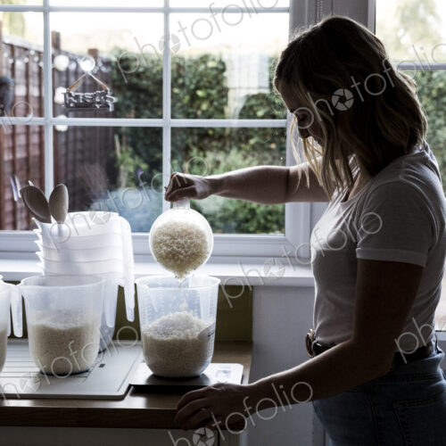 Woman standing in a domestic kitchen, making jar candles.