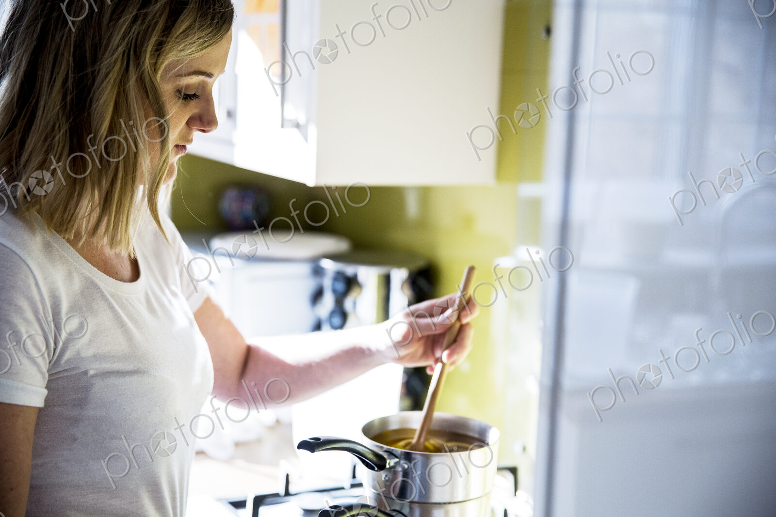 Woman standing in a domestic kitchen, making jar candles.