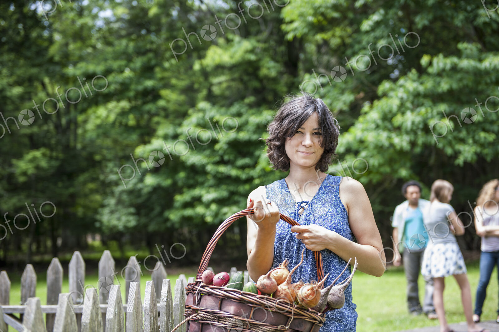 Woman standing in a garden holding a basket of vegetables.