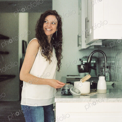 Woman standing in a kitchen preparing a pot of tea.