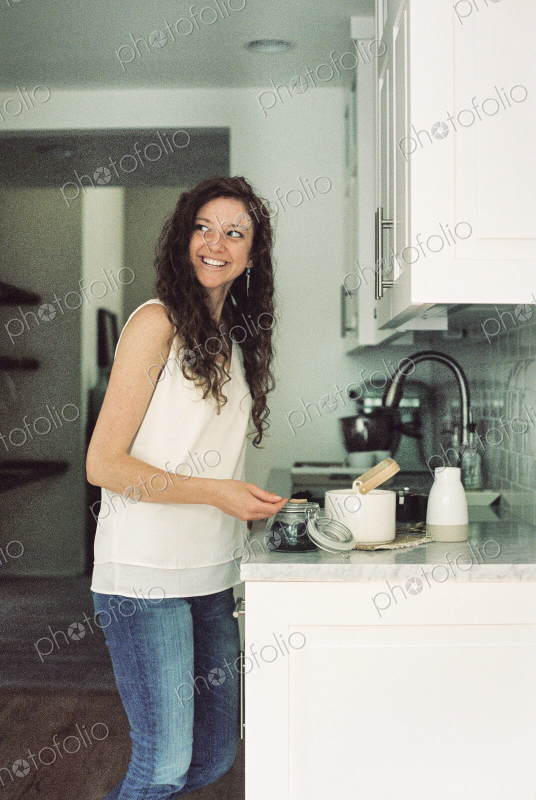 Woman standing in a kitchen preparing a pot of tea.