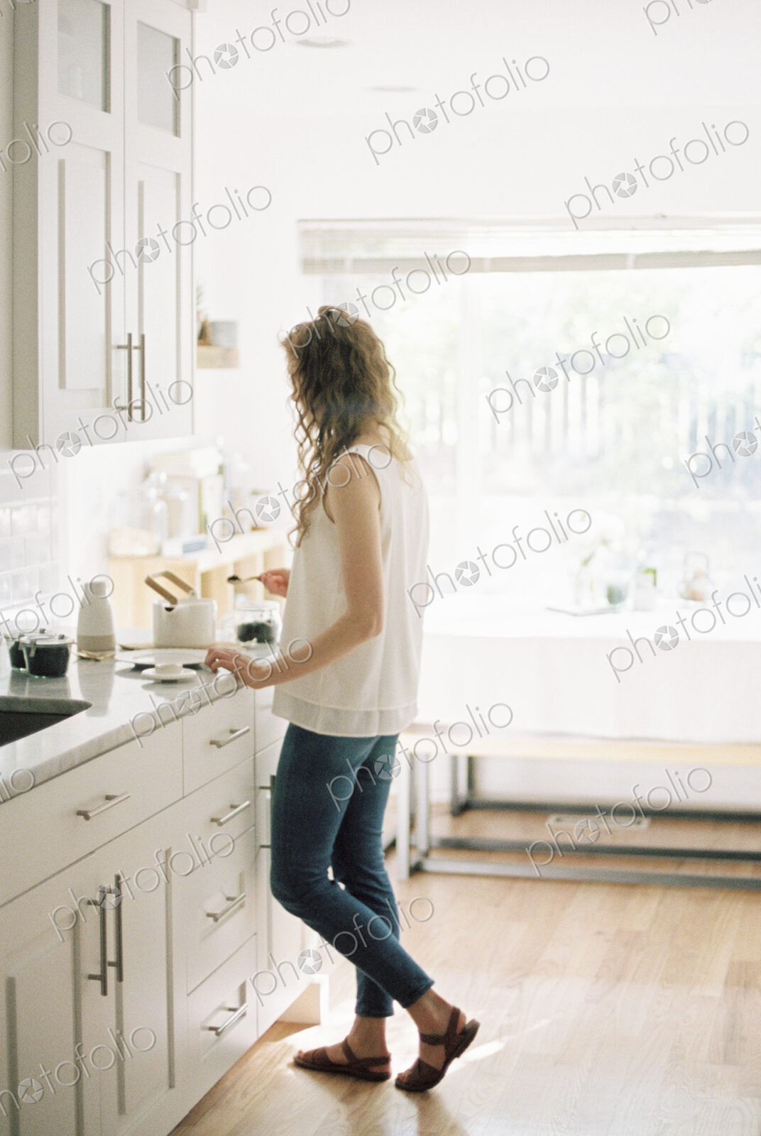 Woman standing in a kitchen preparing a pot of tea.