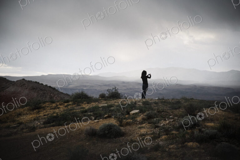 Woman standing in a prairie under a cloudy sky.