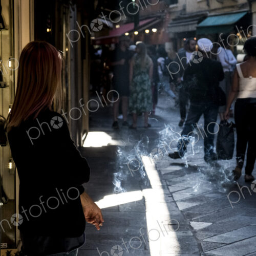 Woman standing in narrow street in Venice, Veneto, Italy, smoking a cigarette. Woman standing in narrow street in Venice, Veneto, Italy, smoking a cigarette.