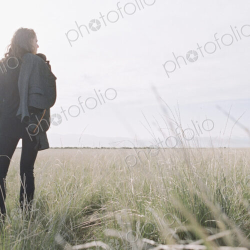 Woman standing looking to the horizon, carrying a jacket and backpack. Woman standing looking to the horizon, carrying a jacket and backpack.