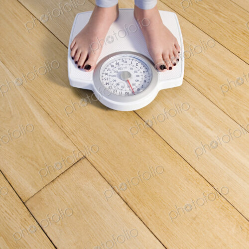 Woman standing on weighing scale, feet and lower legs. Woman standing on weighing scale, feet and lower legs.