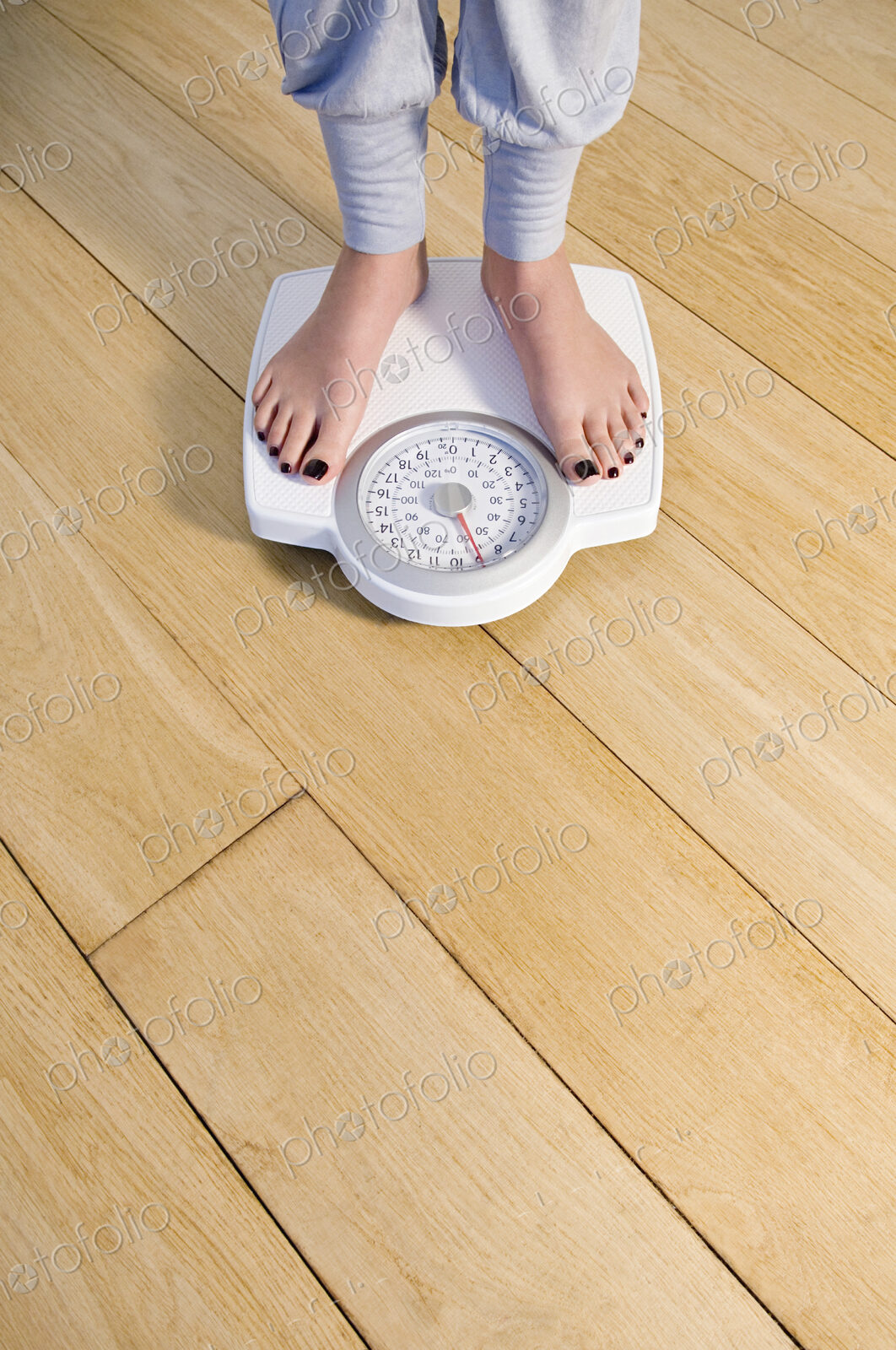Woman standing on weighing scale, feet and lower legs.