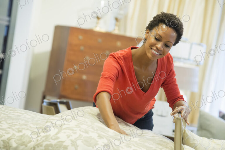Woman straigtening bed with organic sheeting