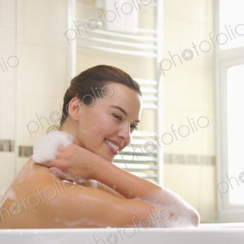 Woman taking a bubble bath, soaping her neck.