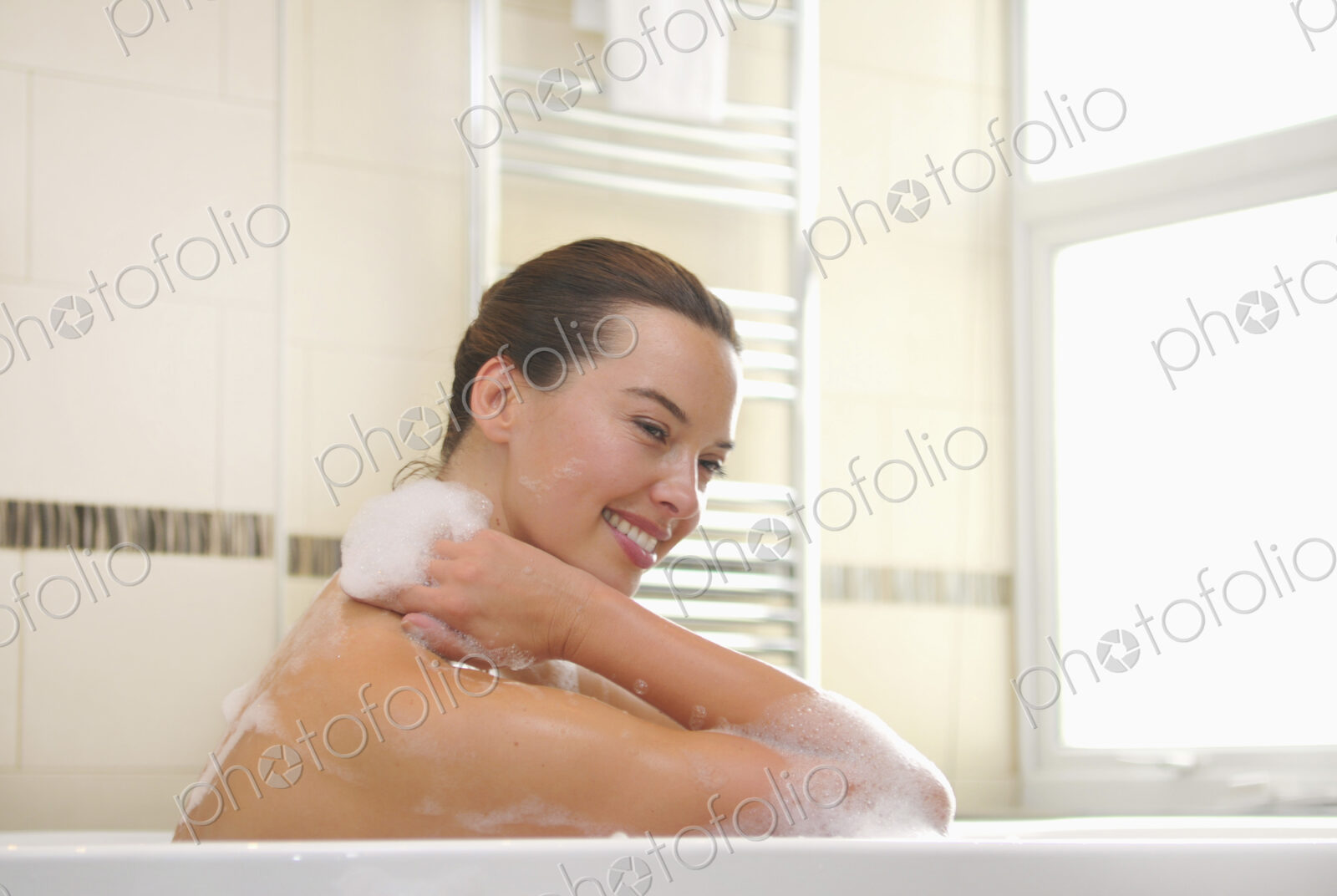 Woman taking a bubble bath, soaping her neck.