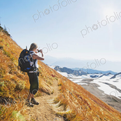Woman taking photograph of remote mountains on hillside
