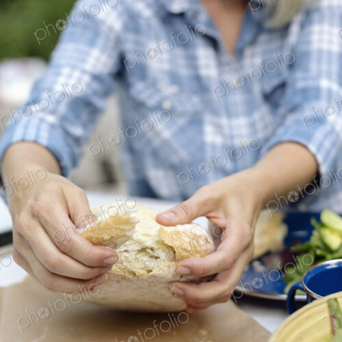 Woman tearing off a piece from a loaf of white bread. Woman tearing off a piece from a loaf of white bread.