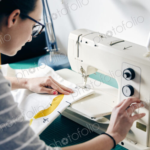 Woman using electric sewing machine to make curtains