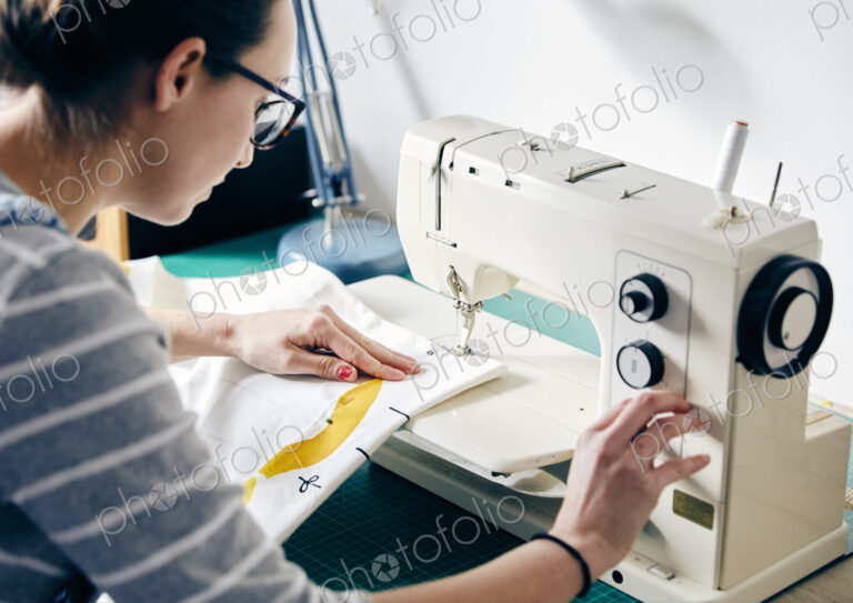 Woman using electric sewing machine to make curtains